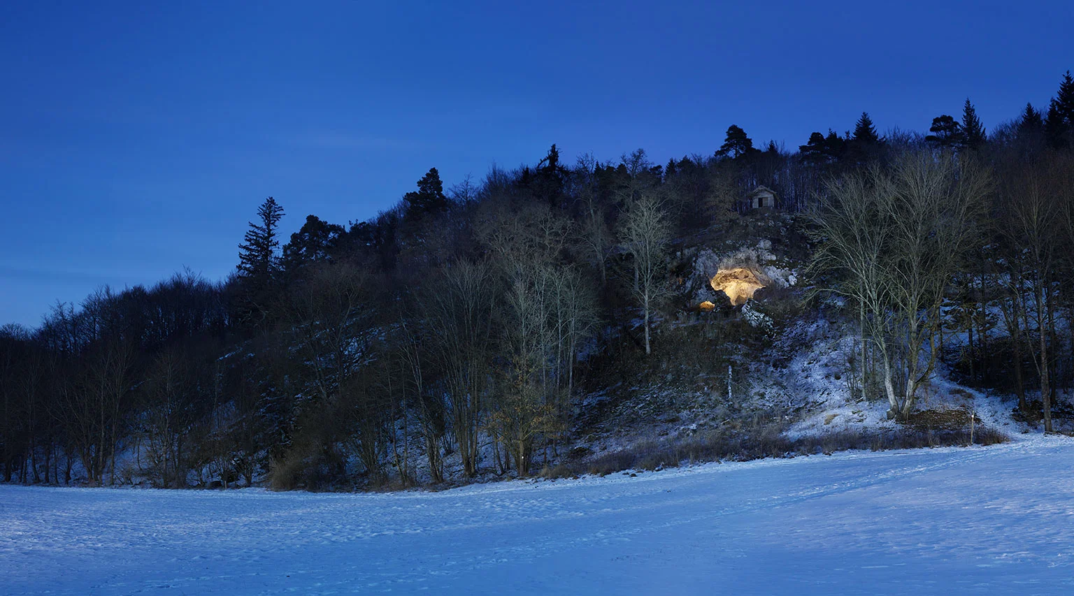 Bockstein Cave in the wintery Lone Valley, with the interior of the cave illuminated
