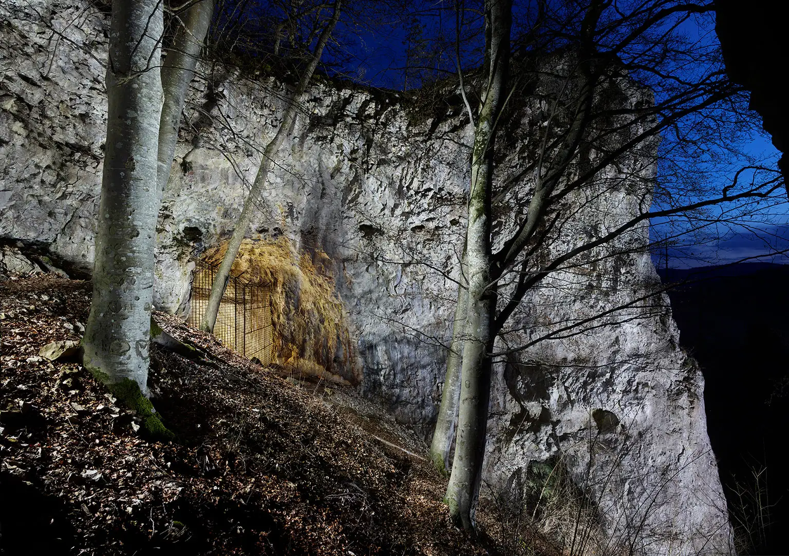 The illuminated Geißenklösterle Cave in the Achtal valley at night