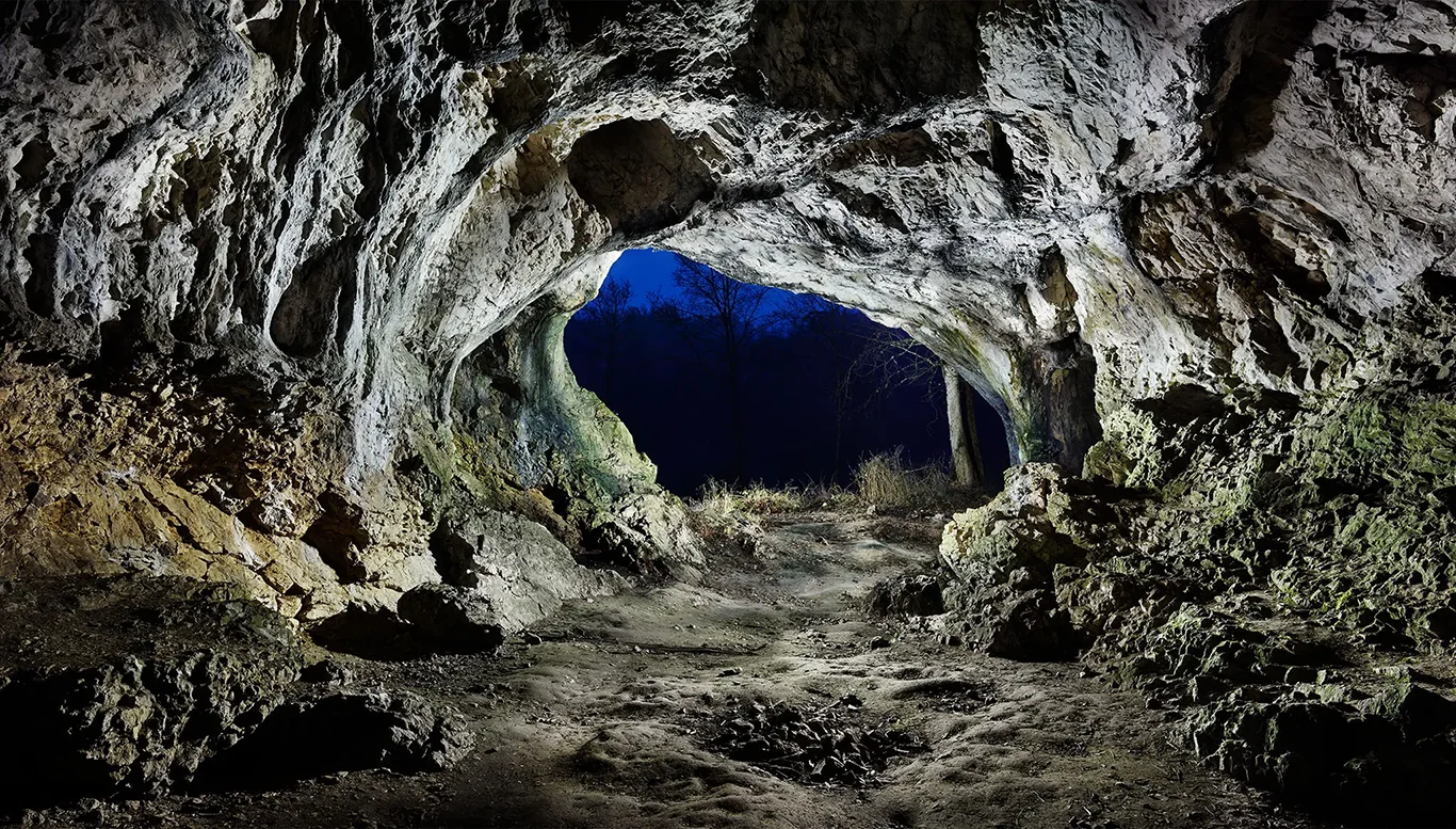 Illuminated interior with a view towards the exit of the Hohlenstein-Stadel Cave in Lonetal