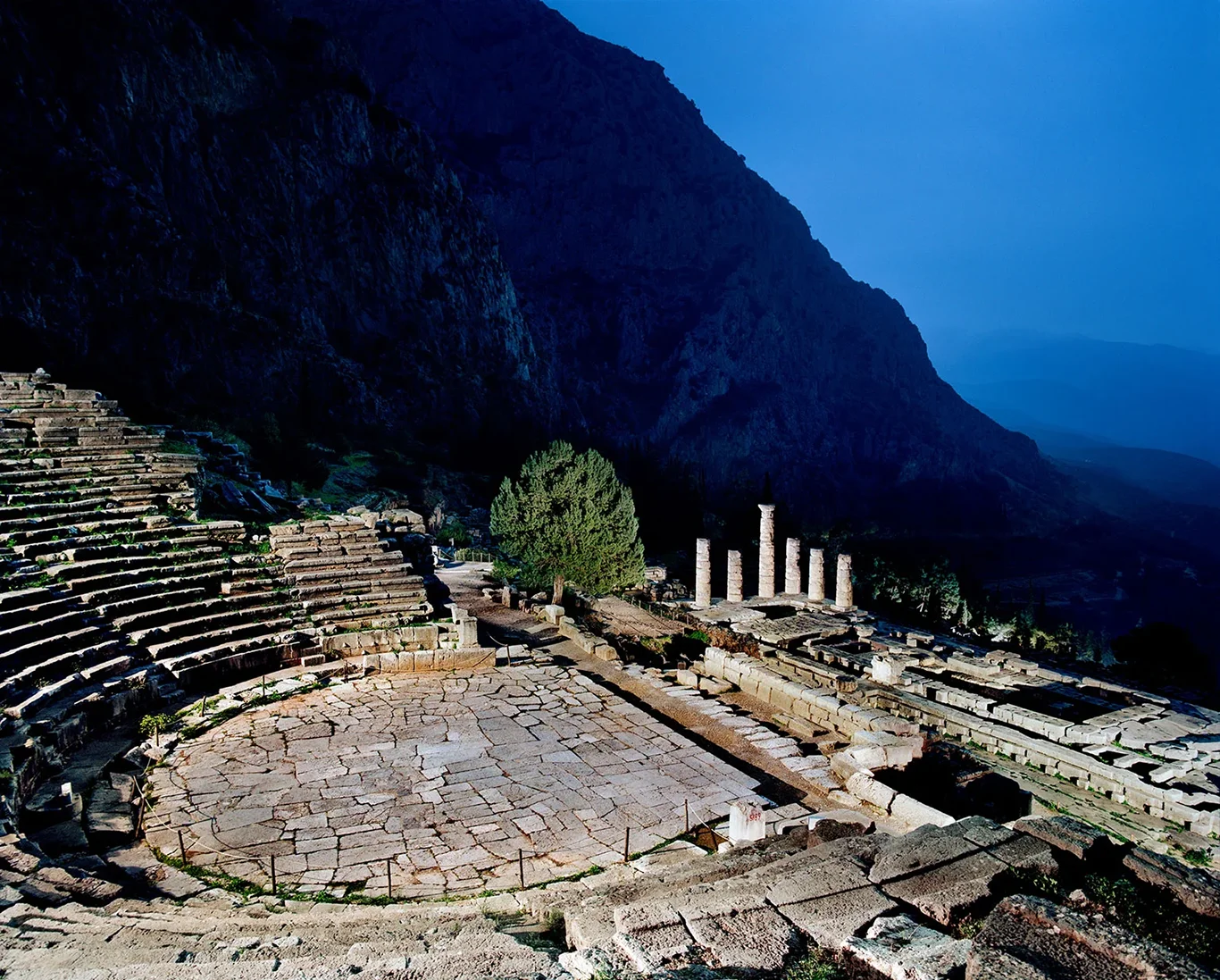 Night photograph of the ancient theatre of Delphi, its stone tiers illuminated against a dark sky