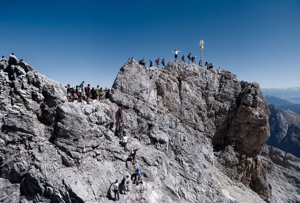 Touristen stehen auf dem Gipfel der Zugspitze, dem höchsten Berg in Deutschland